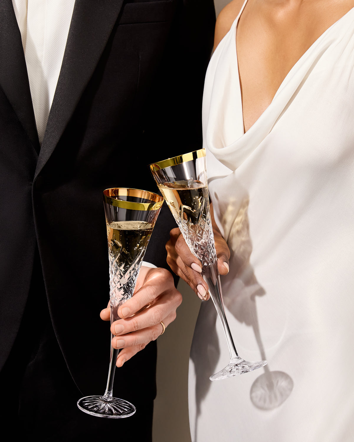 Two people holding champagne glasses in formal attire