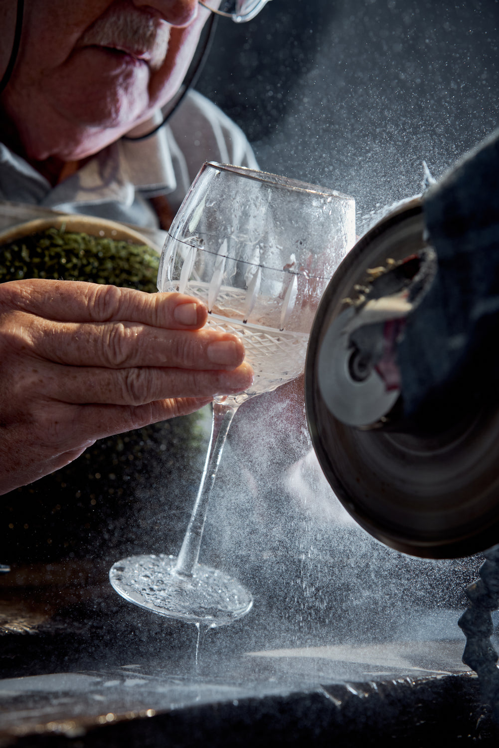 Person cutting a designed cut into a crystal glass.