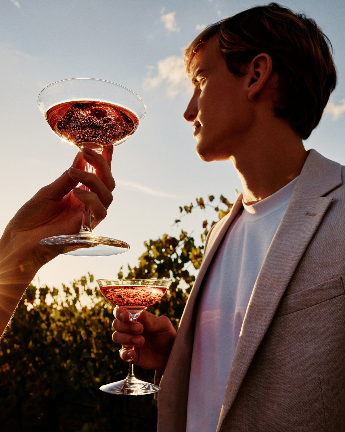 Two people holding cocktail glasses against a scenic background